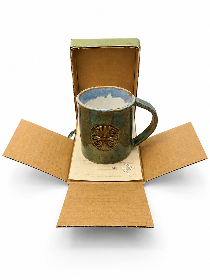 Caja abierta con la taza de cerámica artesanal y su certificado en el interior